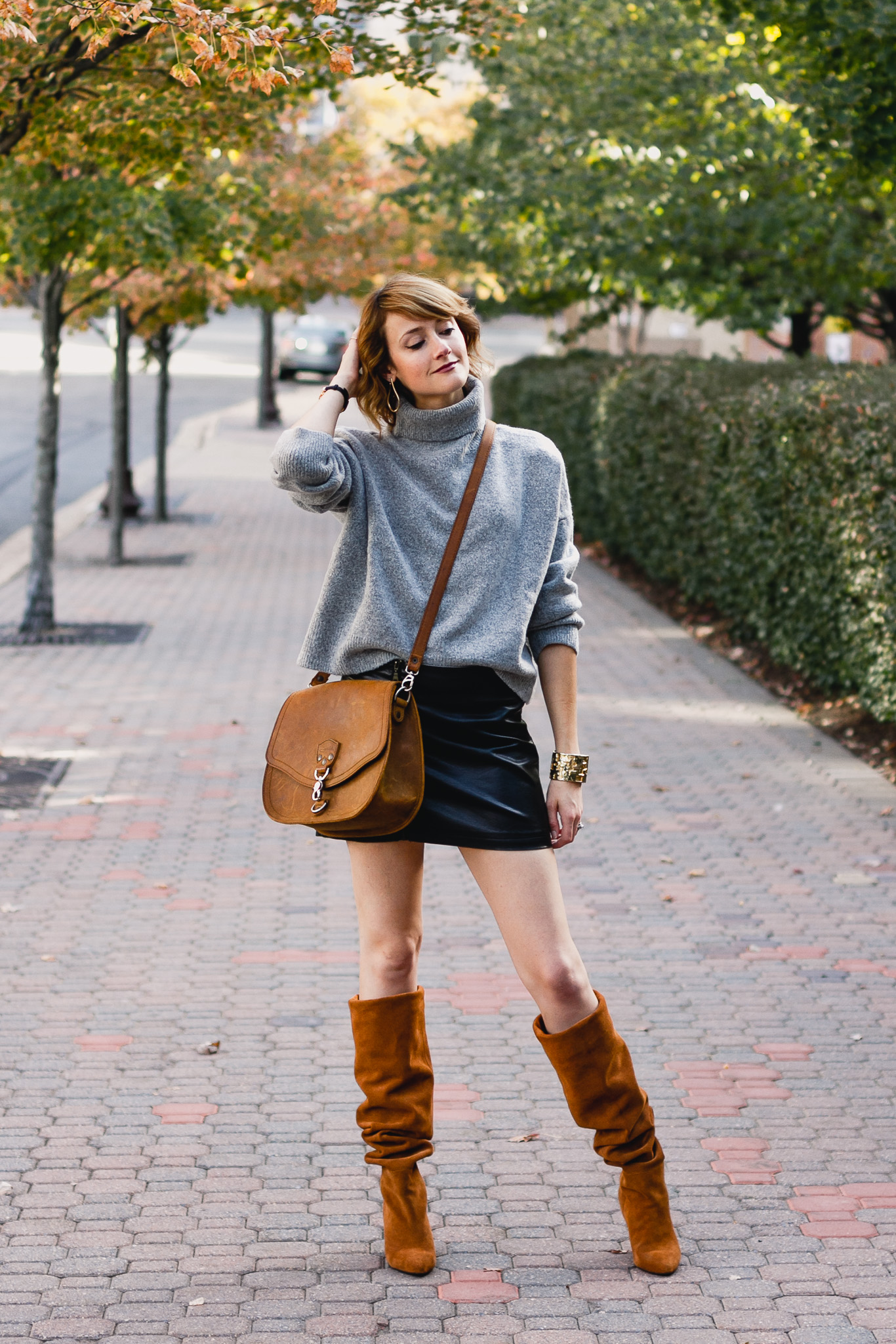 oversized sweater, leather skirt, and slouchy brown boots