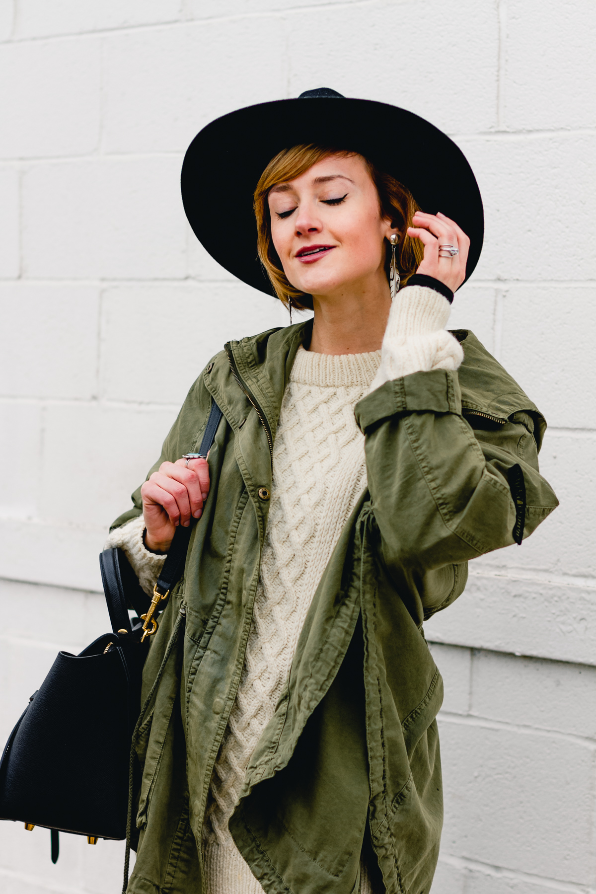 layered anorak, fisherman's knit, and black fedora